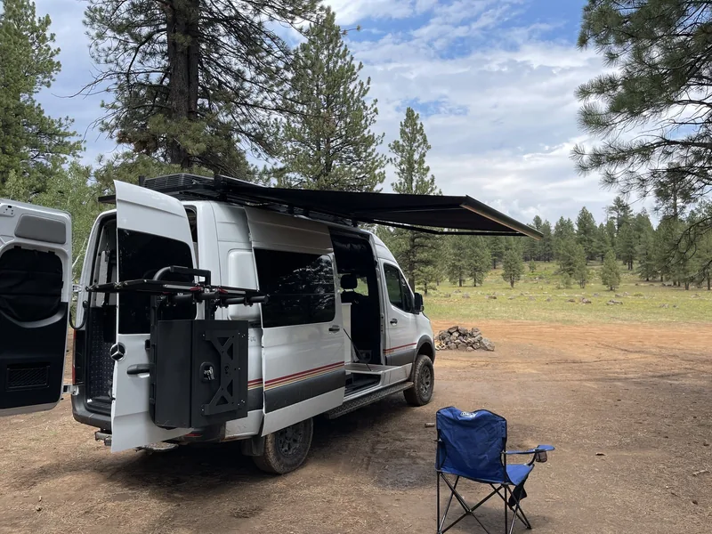 The owner's Storyteller MODE 4x4 parked among the pines with its awning open